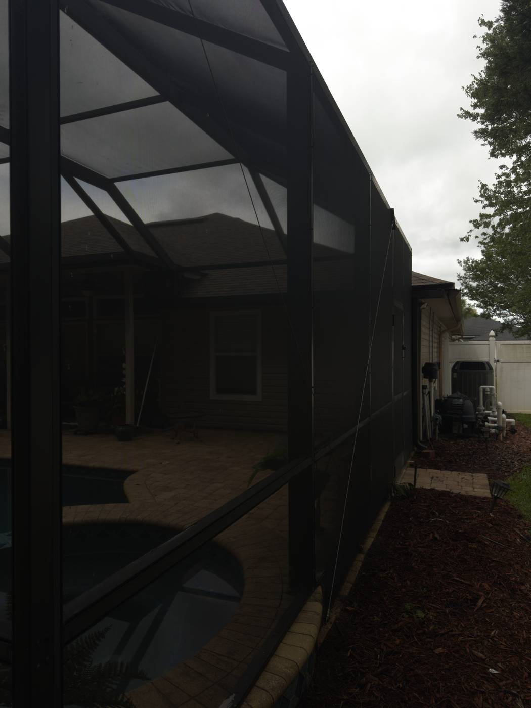 Pool screen enclosure before cleaning, covered in algae